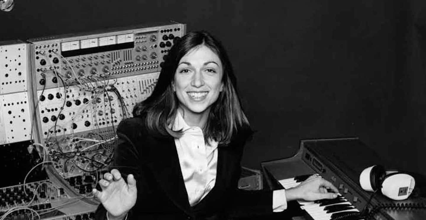 Woman sitting at keyboard in front of synthesizer