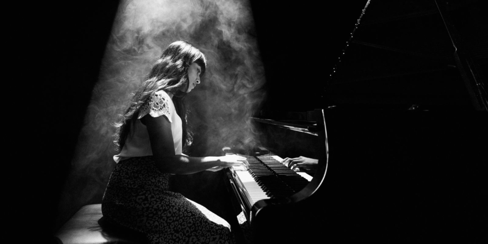 A person sitting under a spotlight playing the piano