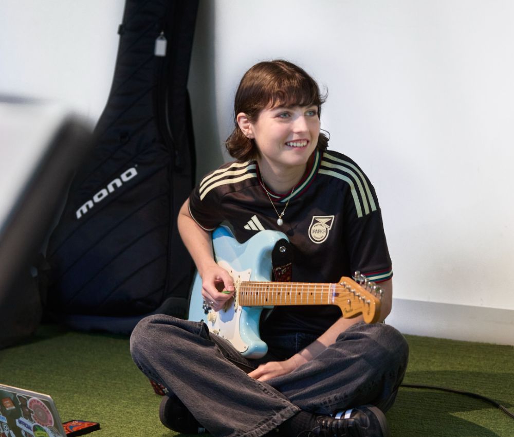Young musician sitting on the floor playing guitar