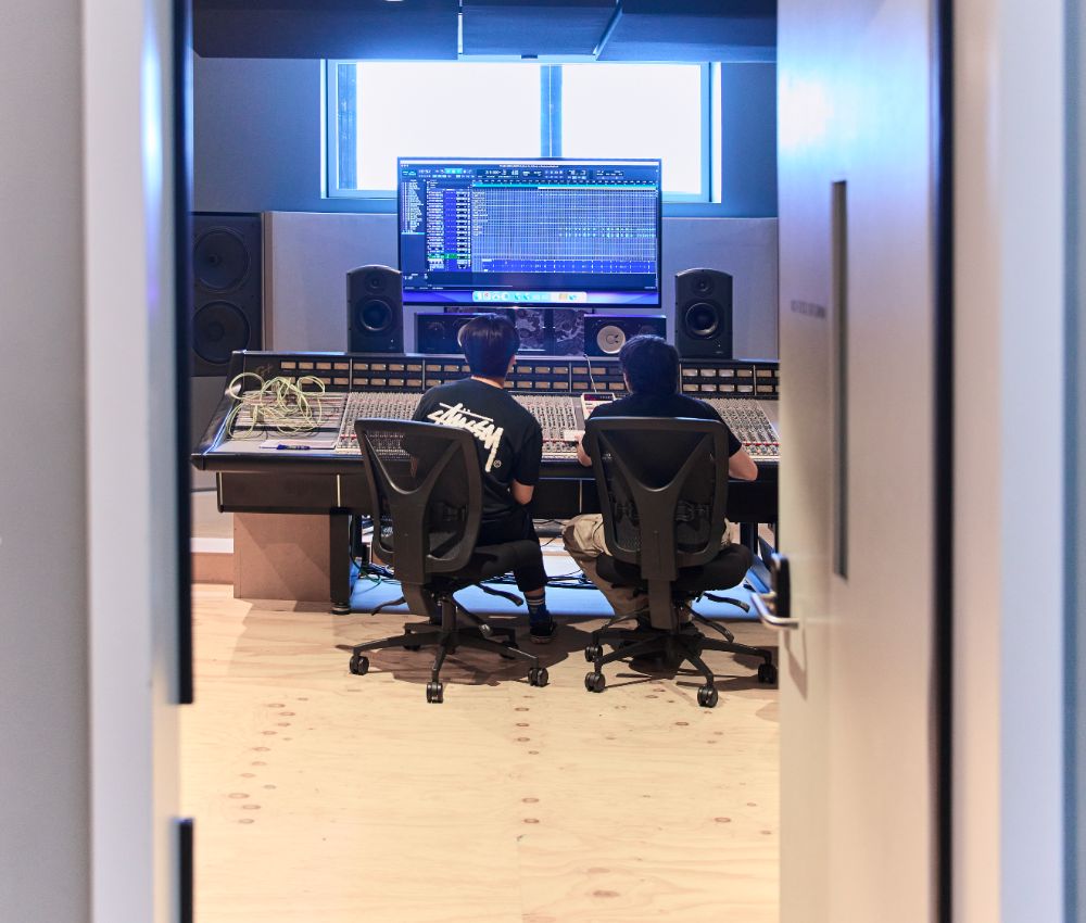 Shot from behind two people sitting in a recording studio