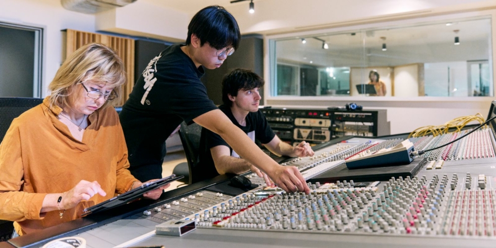 Students and a teacher at a recording studio desk