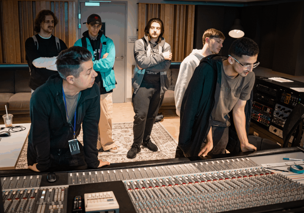 people standing over a mixing desk in a music studio