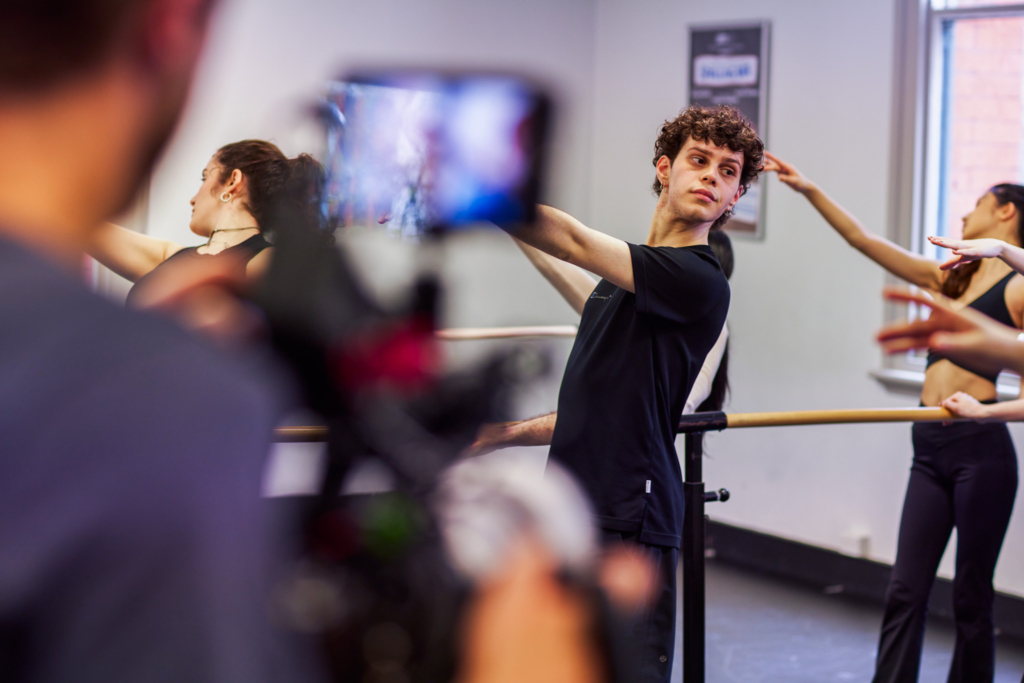 a male student standing by a ballet barre