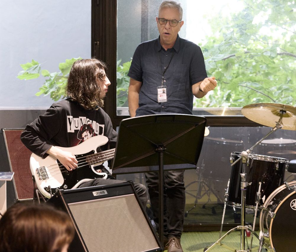 A teacher teaching a student guitar