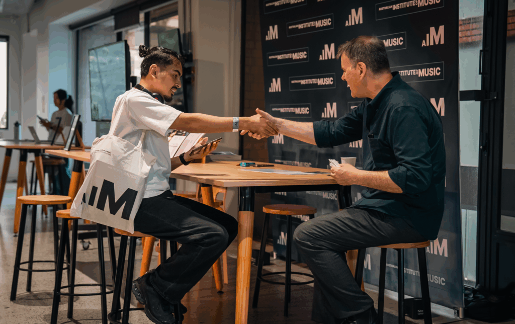 A male student and male teacher shaking hands.