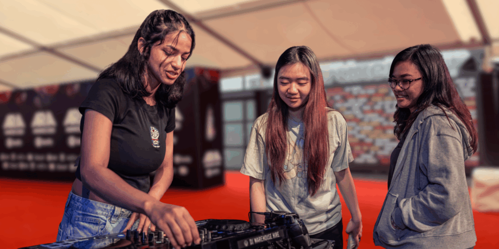 Three students on a red carpet backdrop